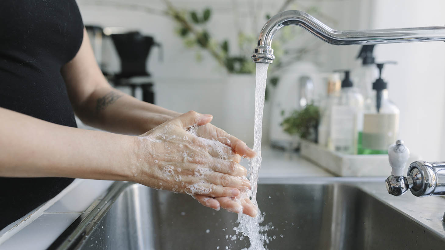 en kvinna som tvättar händerna i ett kök